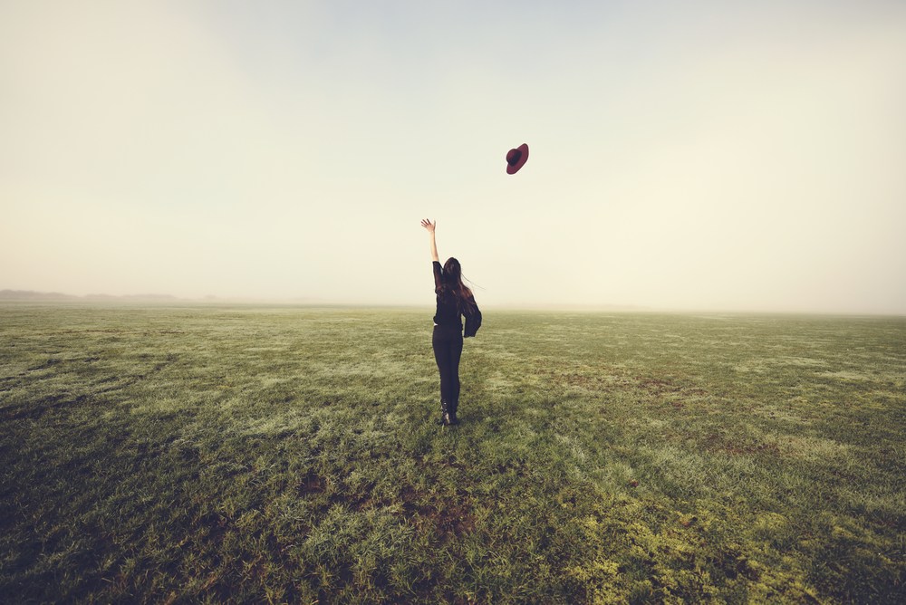 A woman letting go of her hat in the wind to represent letting go after separation