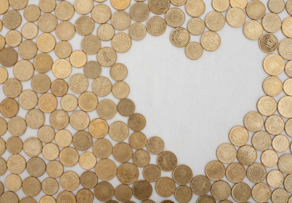 coins laid flat on a table with a gap in the shape of a heart left empty
