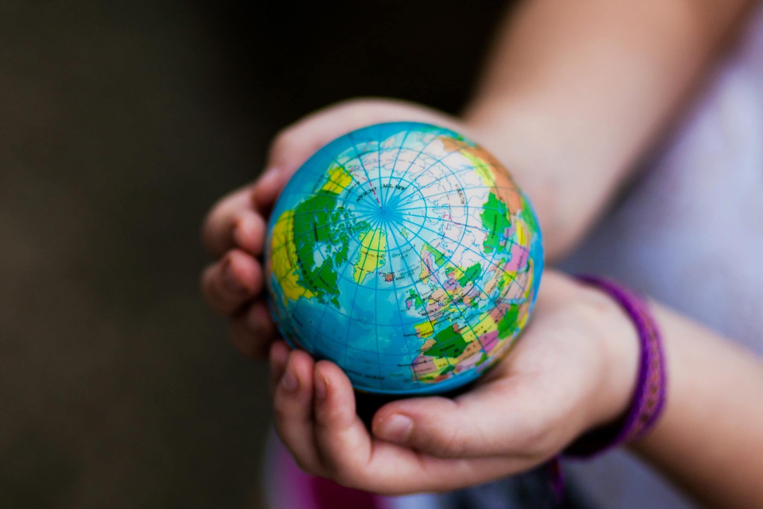 A child's hands holding a globe to represent relocating with children