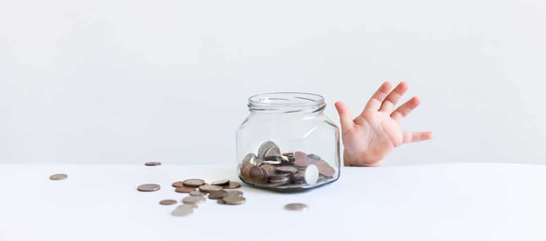 A child's hand reaching above the counter to a jar of money representing child support arrangements.